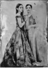 Zwei junge Frauen eine mit langen und eine mit kurzen Haaren in langen Ballkleidern. Schwarz-Weiß