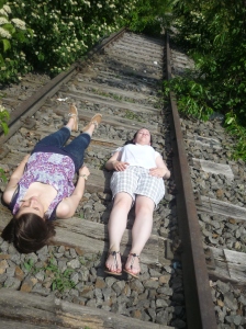 Zwei Frauen liegen auf den Schwellen zwischen zwei Gleisen